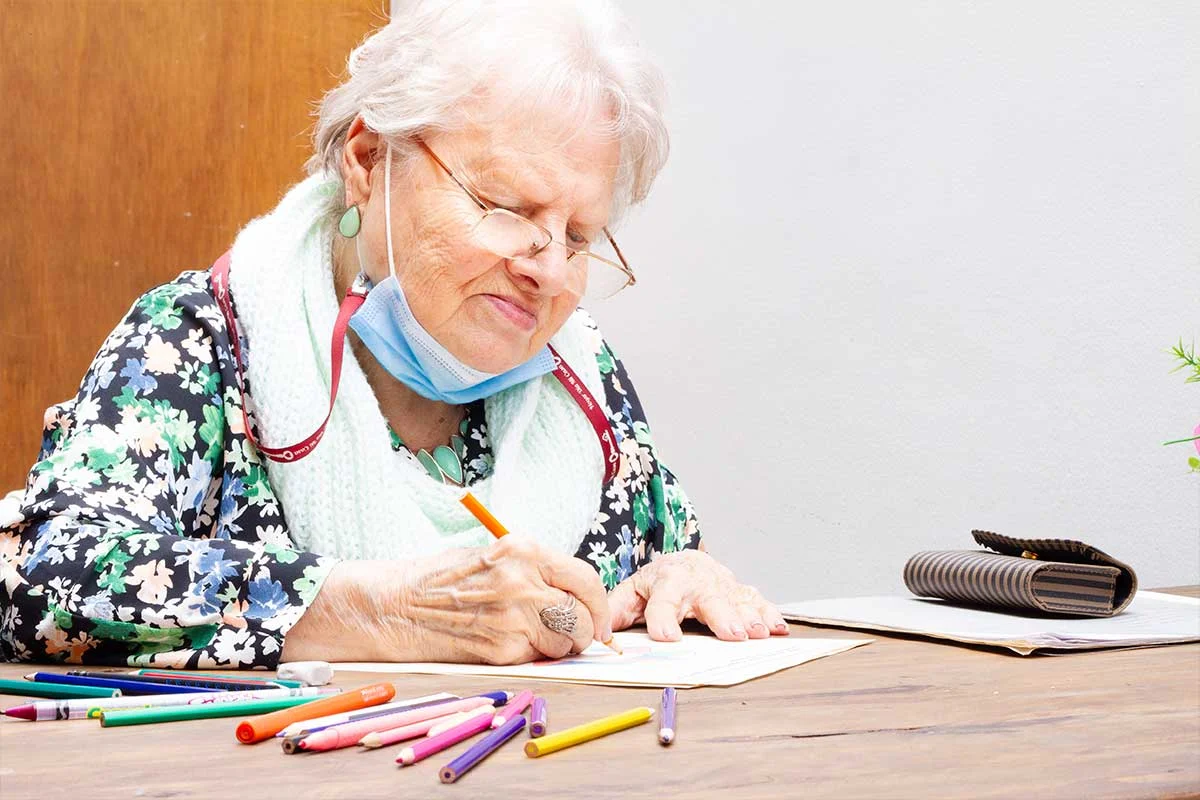 Persona mayor realizando actividades cognitivas con apoyo y materiales visuales